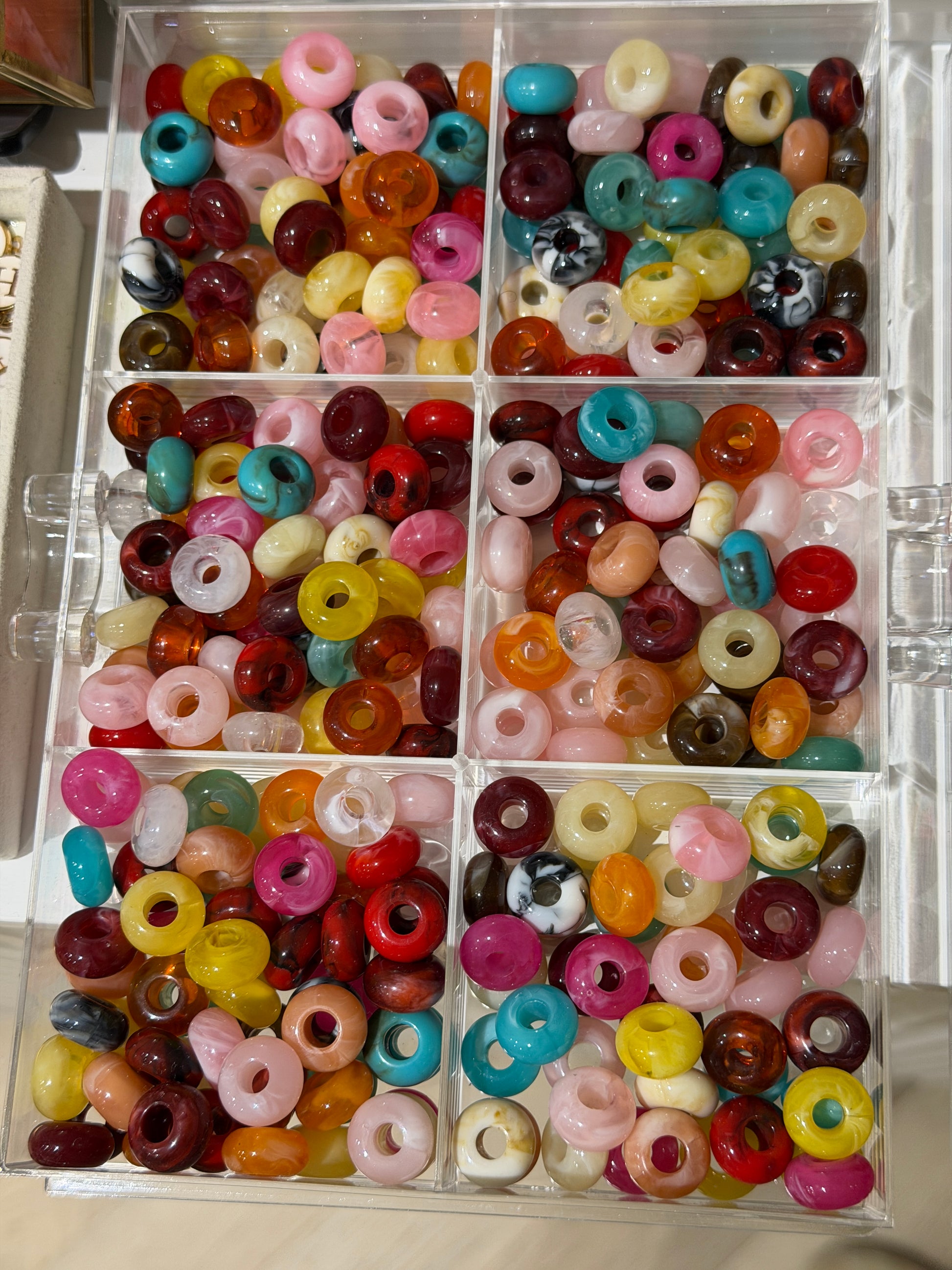 Tray of colourful acrylic beads in pink, red, turquoise and cream for building a bag charm