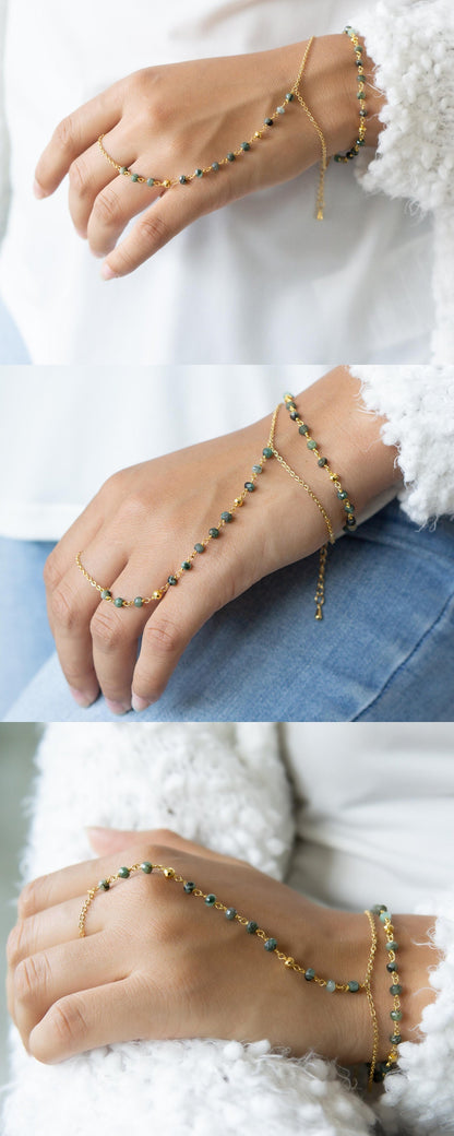 a woman's hand wearing a gold chain bracelet Emerald hand chain for adventurers Gold filled birthstone bracelet for explorers