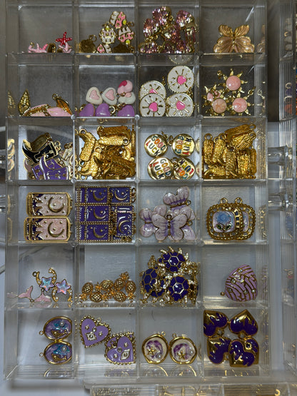 Tray of enamel flower and butterfly charms in pink, purple and gold