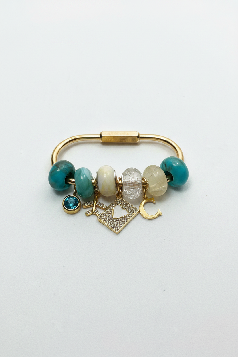 Gold carabiner bag charm with six marbled teal and white beads, an initial L, a pave heart charm and an initial C, made by Breaking Hearts Jewels in Bolton