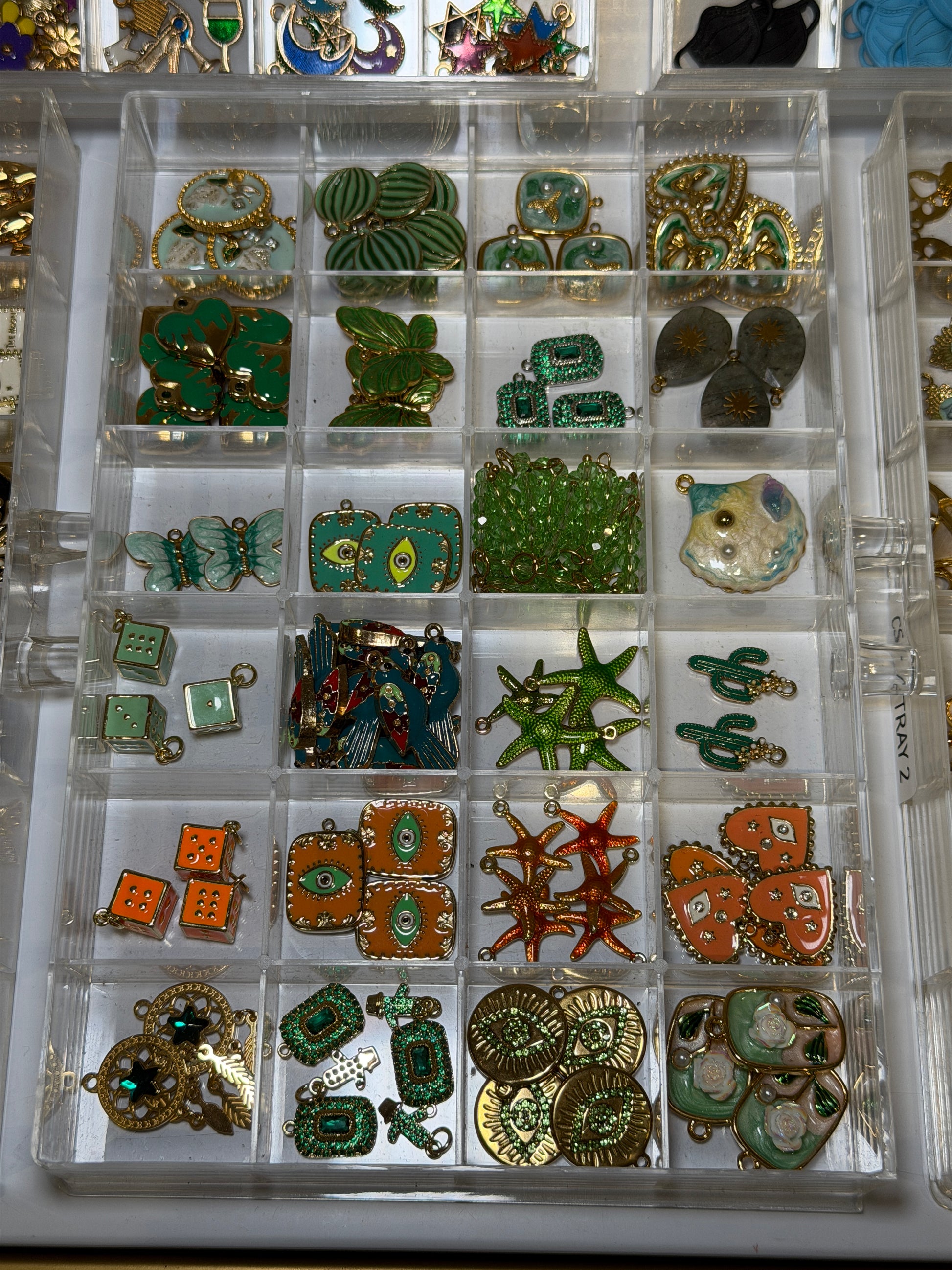 Tray of green and gold charms including turtles, leaves and star shapes