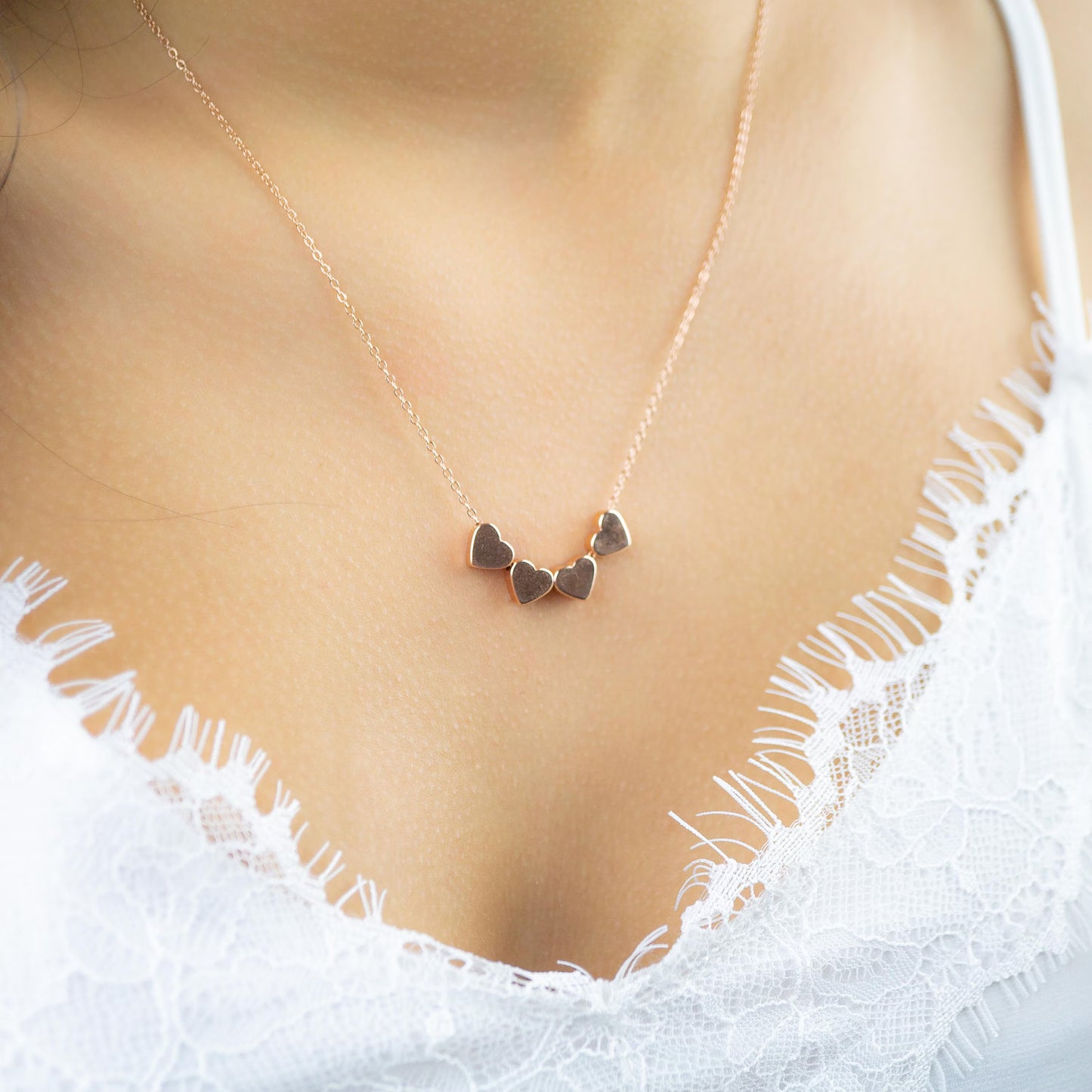 a woman wearing a necklace with two hearts on it