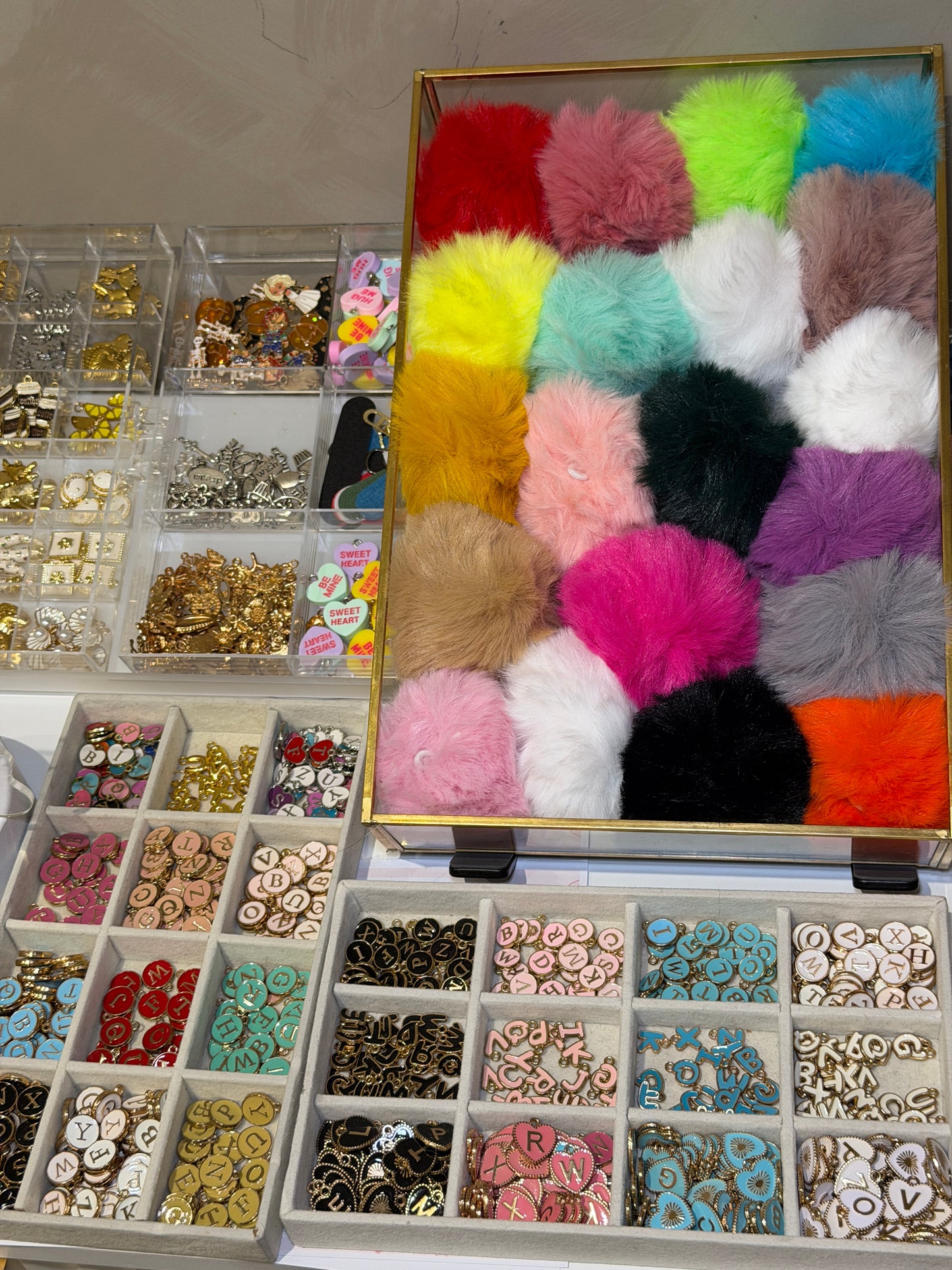 Tray of coloured pom poms and small beads for finishing a bag charm