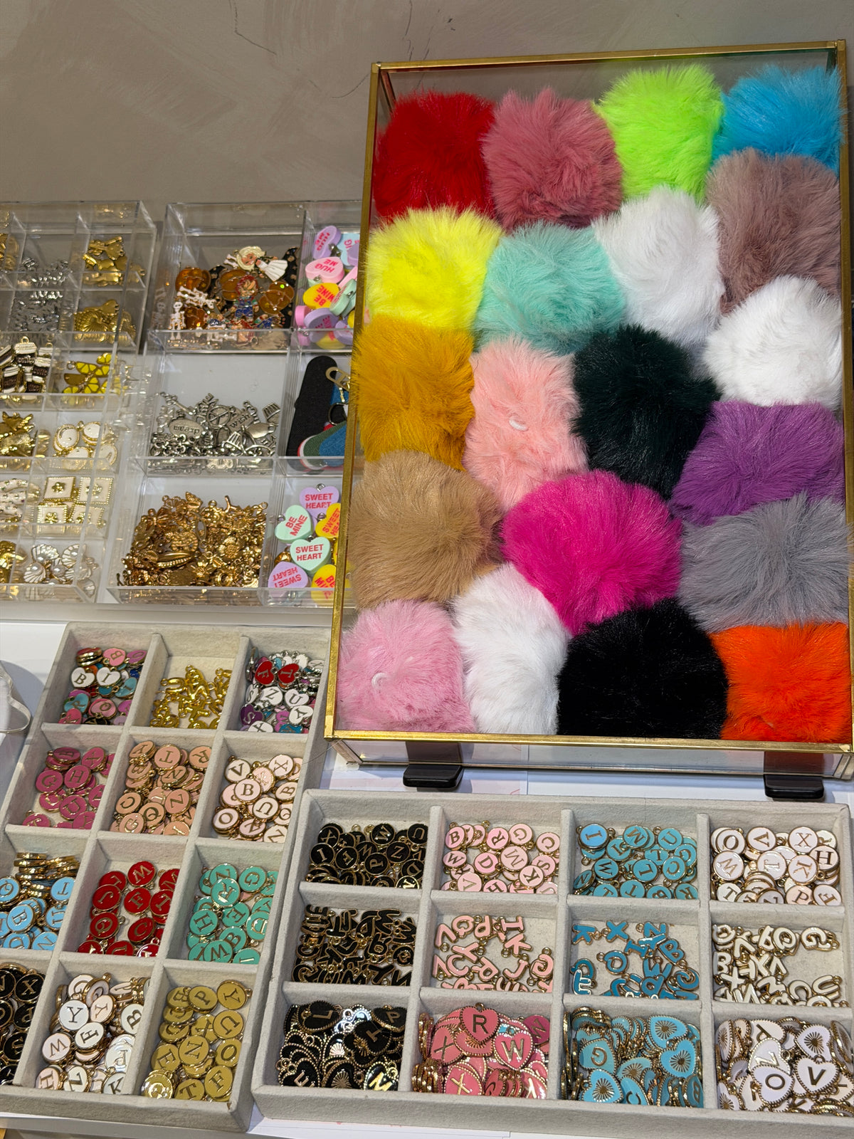 Tray of coloured pom poms and small beads for finishing a bag charm