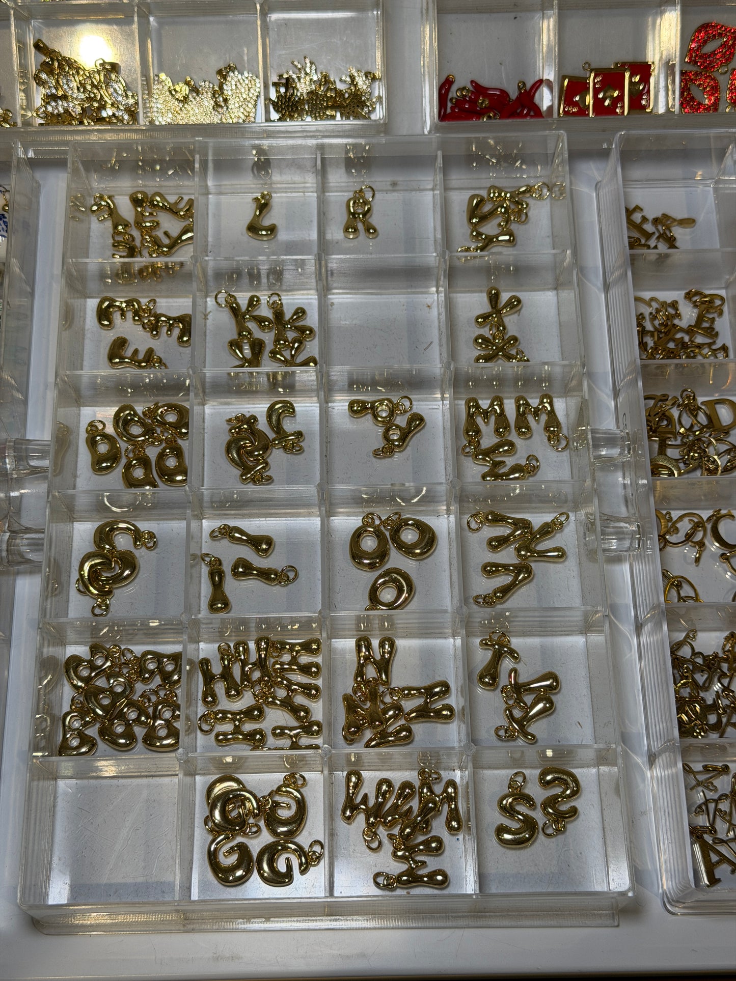 Tray of gold initial and letter charms for personalising a bag charm