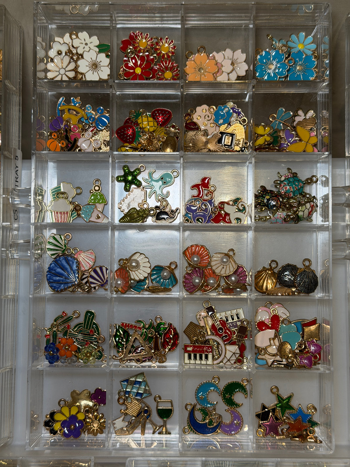 Tray of seaside charms including shells, starfish and white enamel flowers