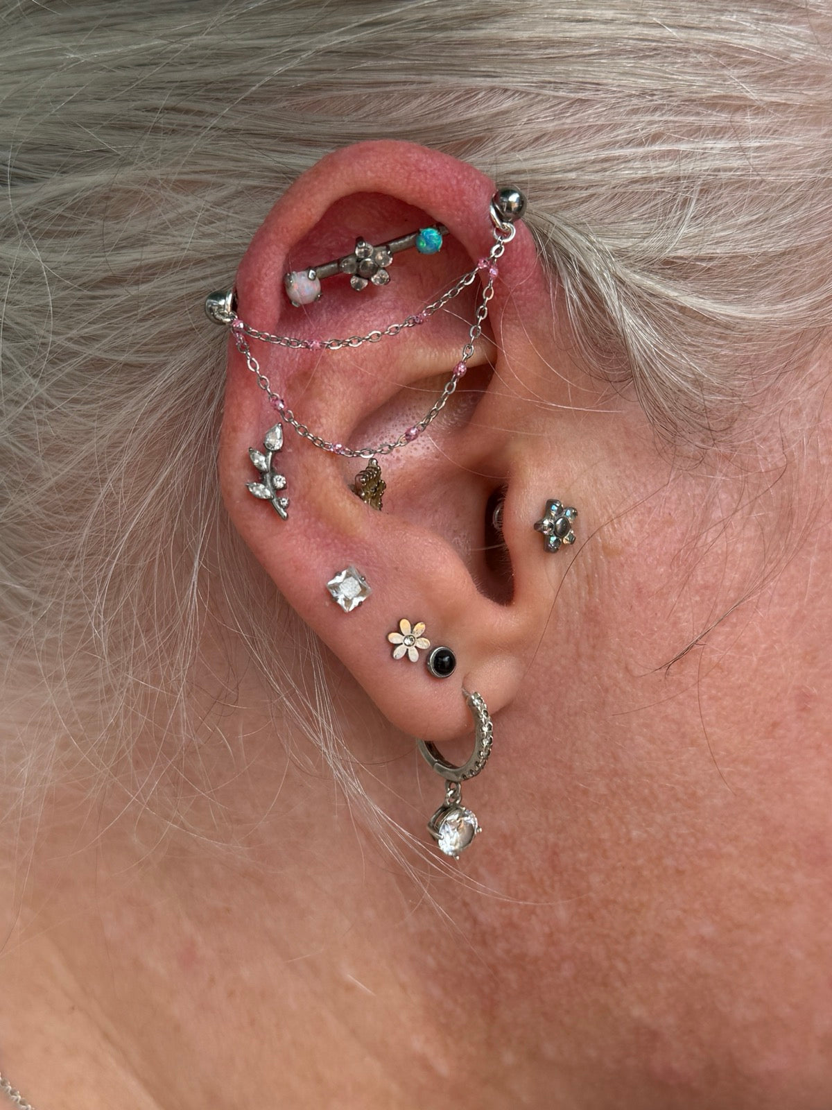 A fine silver ear chain with pink beaded detail, draped across the ear between two piercings