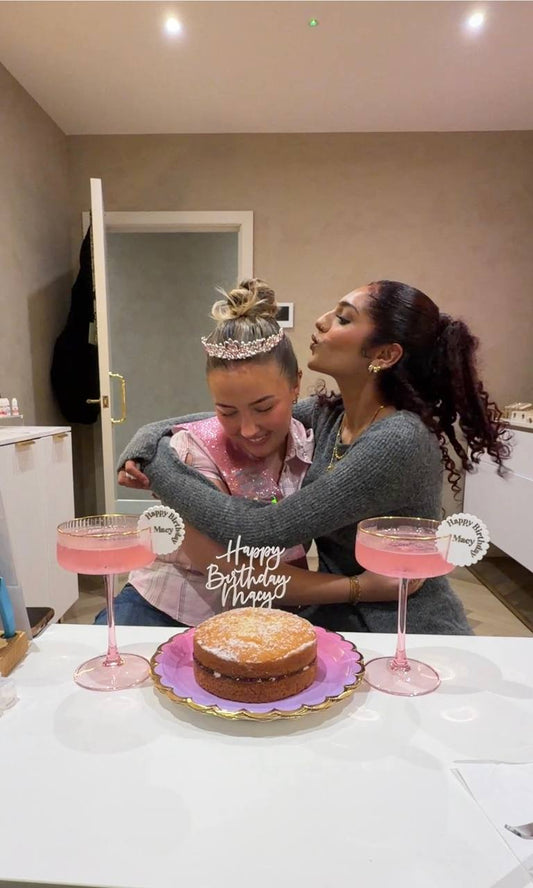 Friends hugging at a birthday celebration in the Breaking Hearts Jewels studio in Bolton, with a birthday cake, personalised cake topper and drink markers